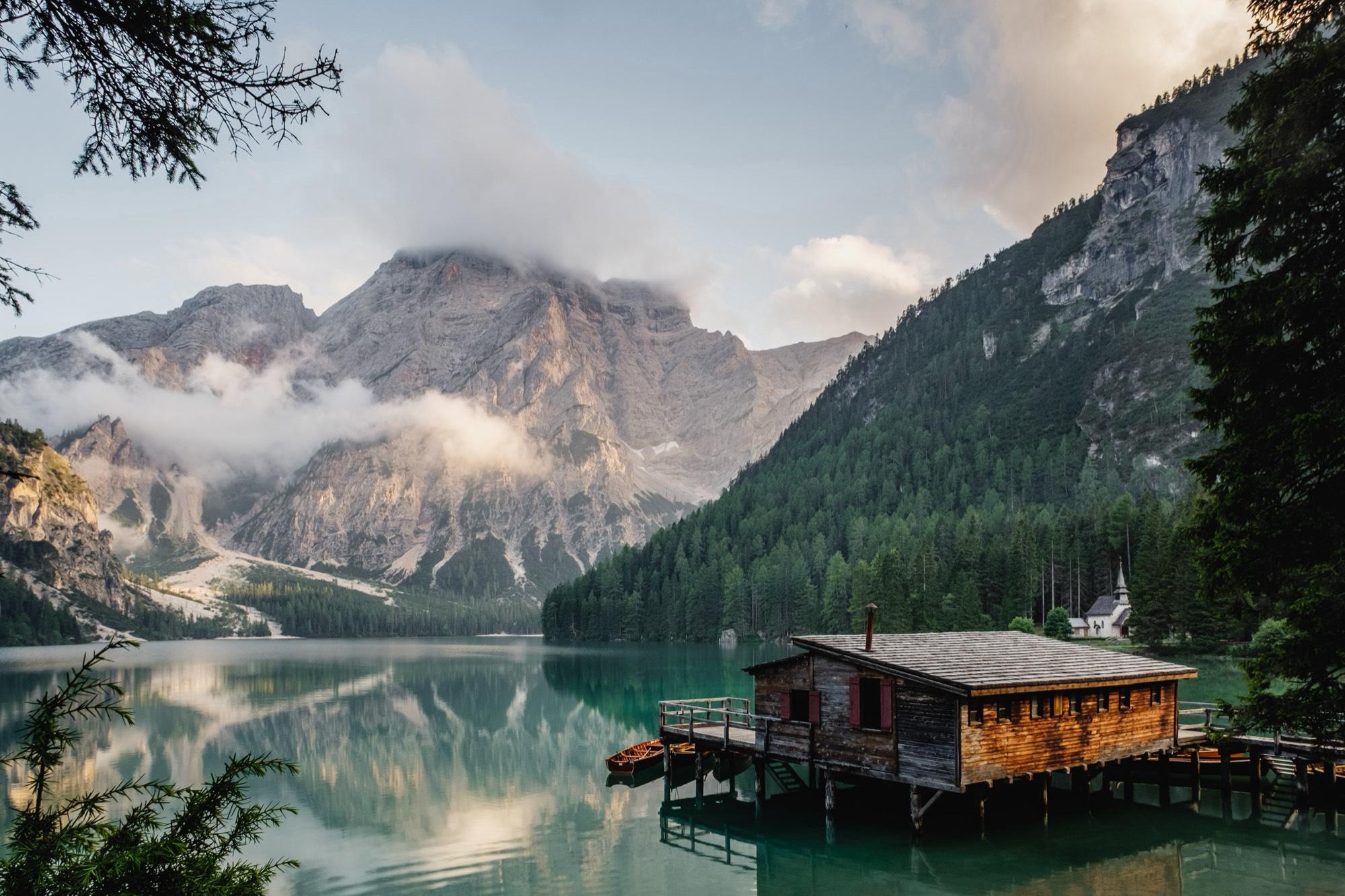 Bootshaus an einem türkisen Bergsee im Morgenlicht