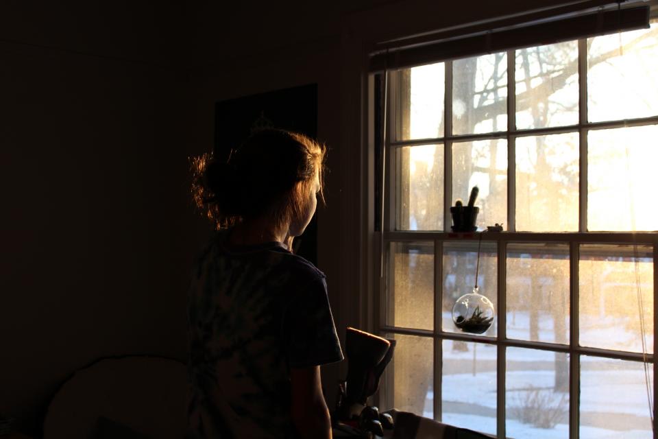 Eine Frau steht am Fenster im Abendlicht